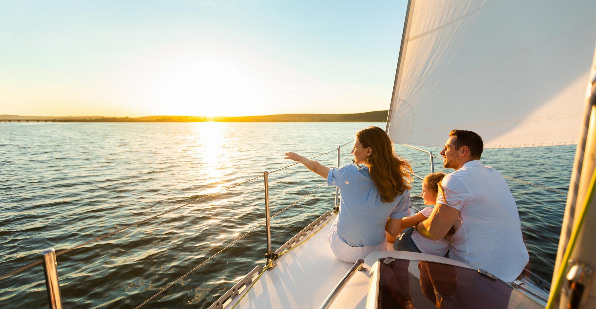 Family enjoying time together on a sailboat at sunset